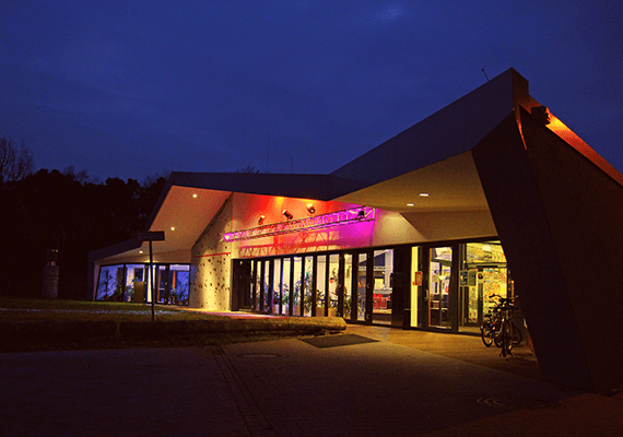 Bild der beleuchteten Frontseite des JuKuZ Mörfelden bei Nacht